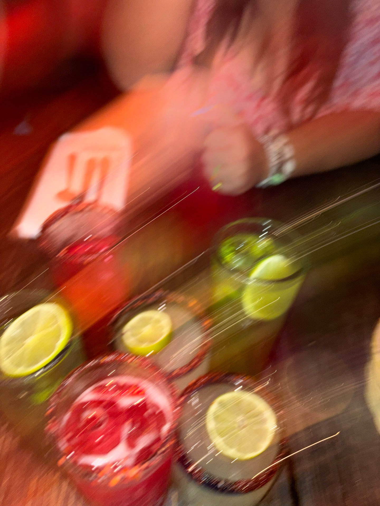 Cocktails and lime wedges on a dim bar table, shot on film with motion blur