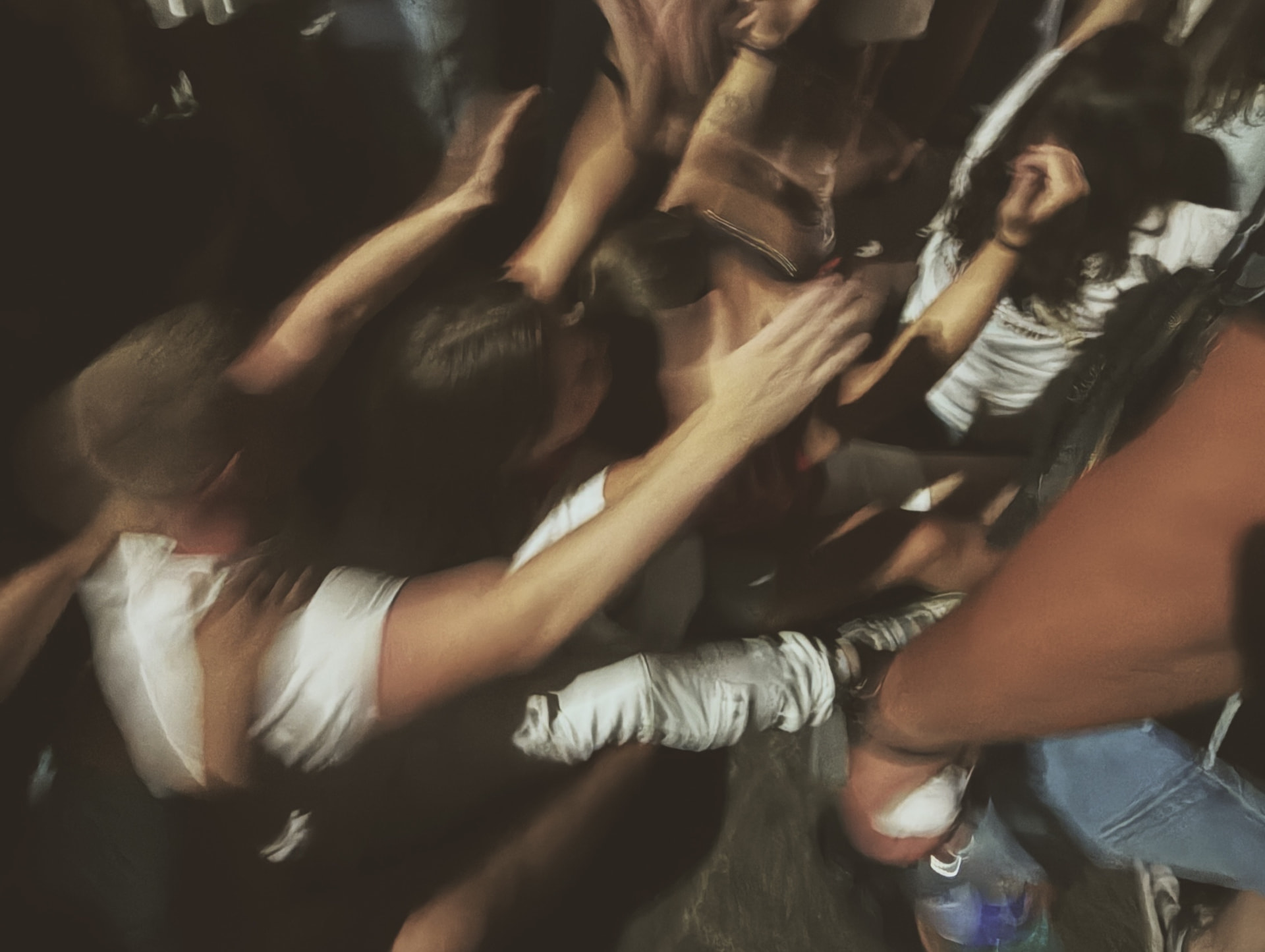A packed crowd dancing in the dark, grainy overhead film photo